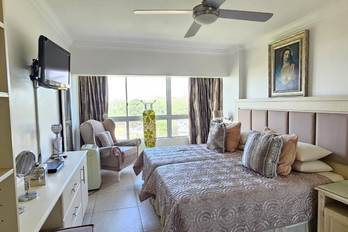 A well-lit bedroom featuring tiled flooring, a ceiling fan, and built-in storage cabinetry with an integrated headboard.