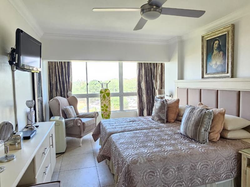 A well-lit bedroom featuring tiled flooring, a ceiling fan, and built-in storage cabinetry with an integrated headboard.