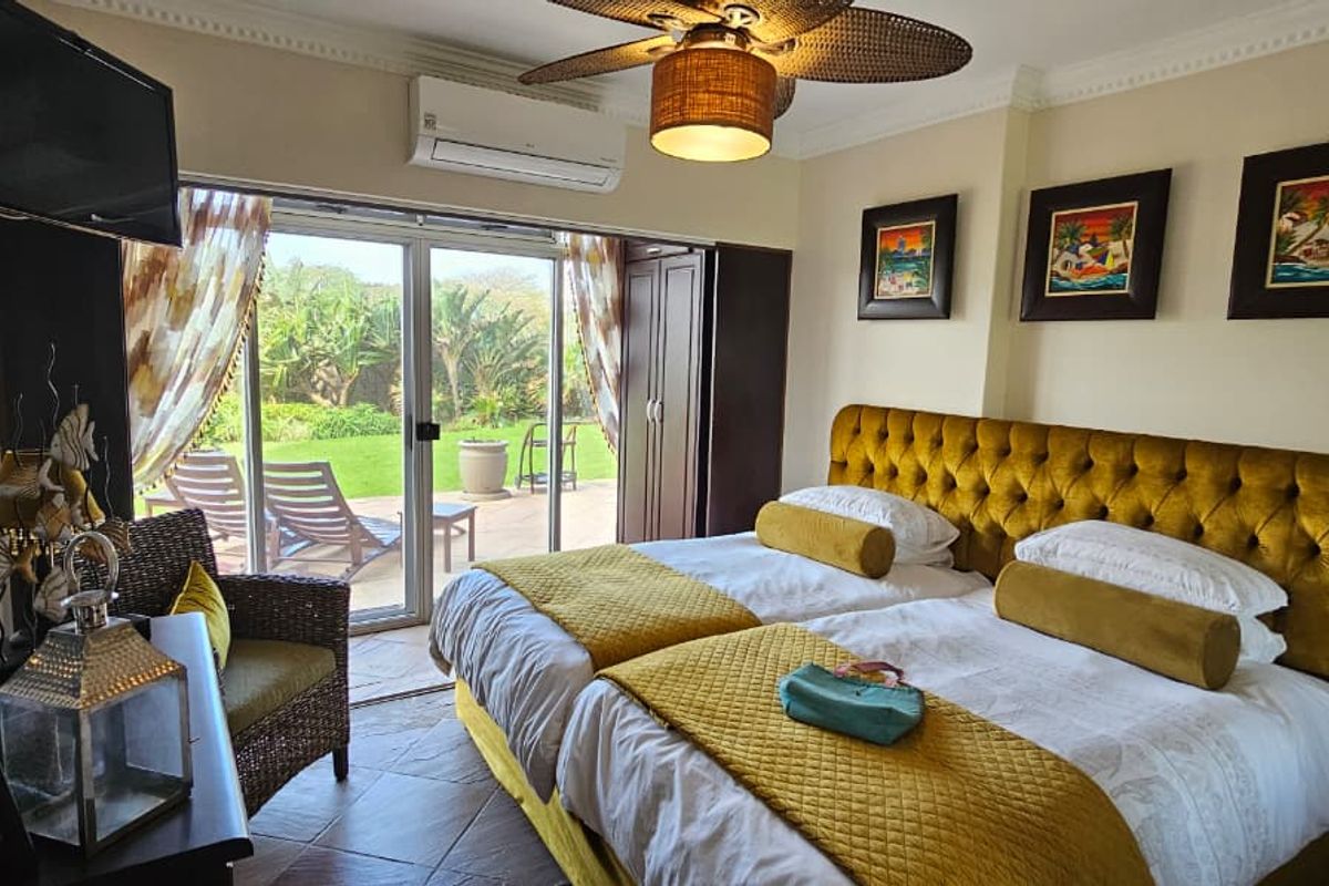 A well-maintained bedroom featuring tiled floors, a ceiling fan, split-system air conditioning, and sliding glass doors providing direct access to an outdoor patio area.