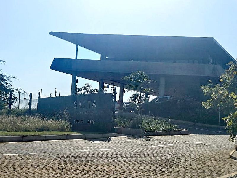 The entrance to Salta South Gate, featuring a modern architectural gatehouse, paved access road, and established perimeter security fencing.