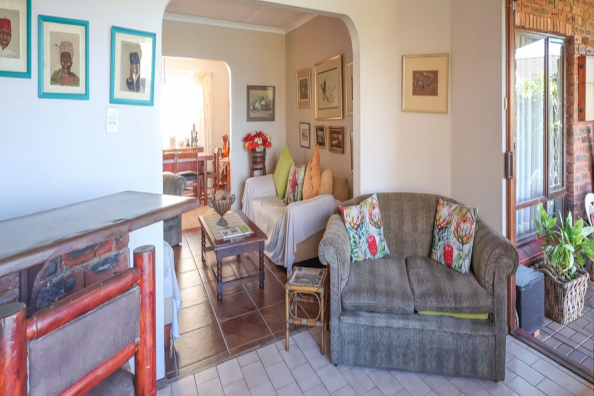 A cozy living room featuring a brick fireplace, tiled flooring, and an archway leading to an adjacent dining area with access to the patio.
