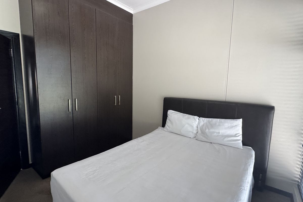 A bedroom featuring dark wood built-in cupboards and neutral wall finishes, providing functional storage space.