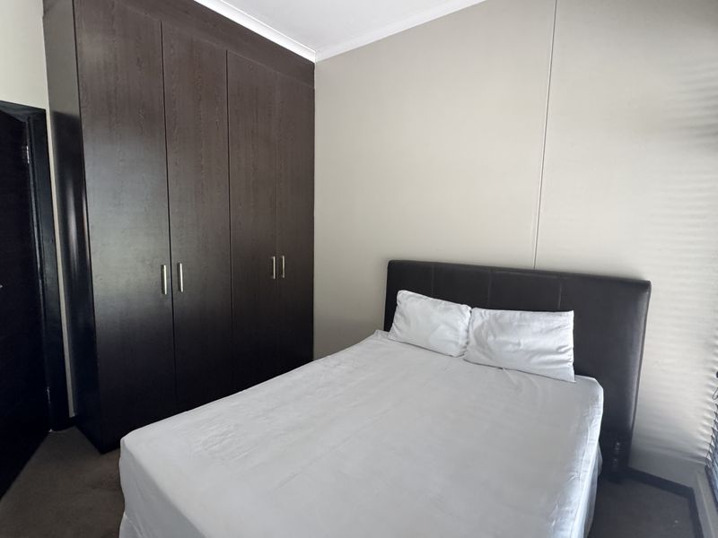A bedroom featuring dark wood built-in cupboards and neutral wall finishes, providing functional storage space.