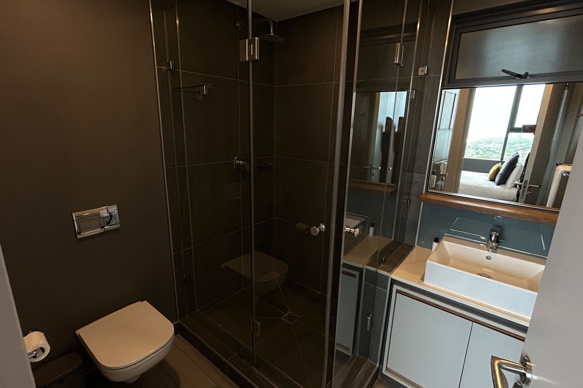 Modern bathroom featuring a glass-enclosed shower, wall-hung toilet, and a contemporary vessel sink vanity with integrated storage.