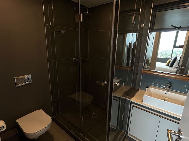 Modern bathroom featuring a glass-enclosed shower, wall-hung toilet, and a contemporary vessel sink vanity with integrated storage.