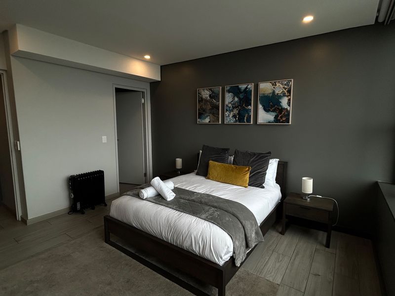 A modern, well-maintained bedroom featuring neutral tones, recessed lighting, and large windows, creating a comfortable and contemporary living space.