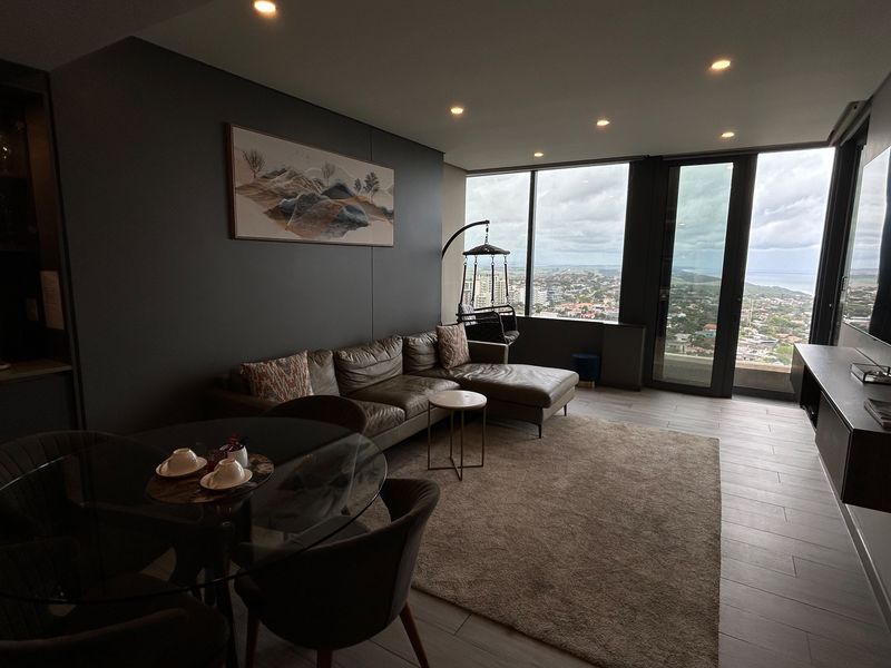 Modern open-plan living area featuring floor-to-ceiling windows with expansive views, recessed lighting, and sleek tiled flooring in a contemporary apartment setting.
