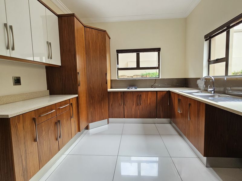 Modern kitchen featuring wood-grain and white cabinetry, stone countertops, tiled flooring, and a double sink with a sleek mixer tap.