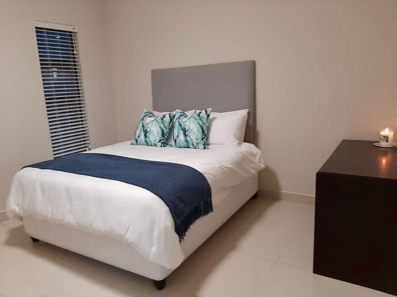 A well-maintained bedroom featuring neutral wall tones, tiled flooring, and fitted venetian blinds, offering a clean and functional living space.