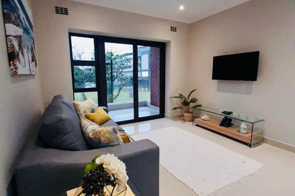 A well-maintained living room featuring tiled flooring, recessed downlighting, and a large sliding glass door providing access to the outdoor area.