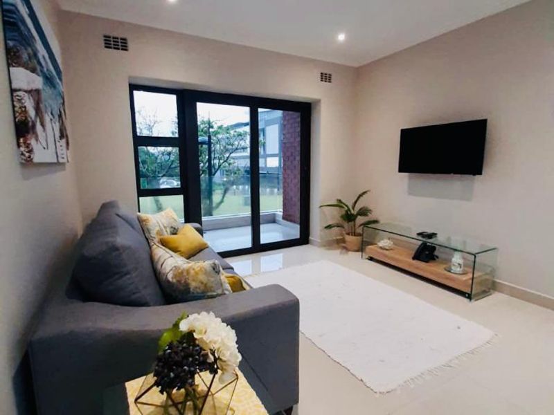 A well-maintained living room featuring tiled flooring, recessed downlighting, and a large sliding glass door providing access to the outdoor area.