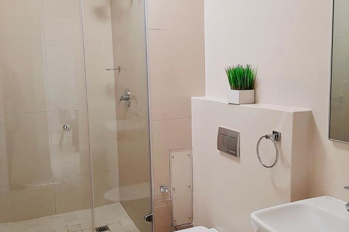 A modern, well-maintained bathroom featuring a glass-enclosed shower, wall-mounted toilet, and a sleek vanity basin with contemporary fixtures.