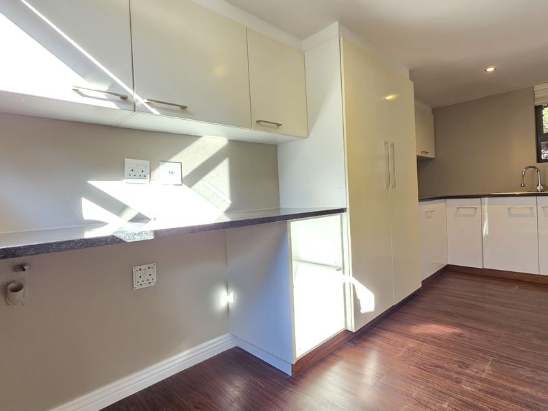 A clean, functional kitchen featuring modern laminate cabinetry, dark countertops, and wood-look flooring, offering a bright and well-maintained space ready for personalization.
