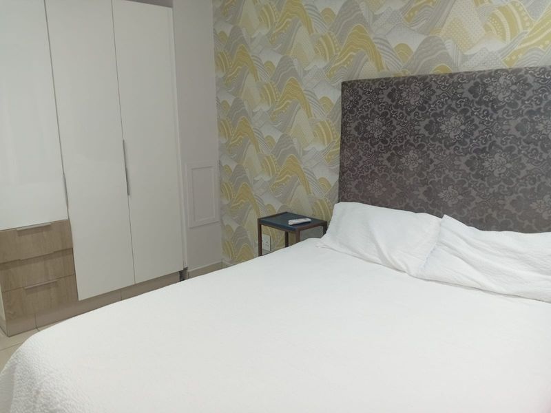 A well-maintained bedroom featuring a built-in wardrobe and decorative patterned wallpaper, providing a clean and functional living space.