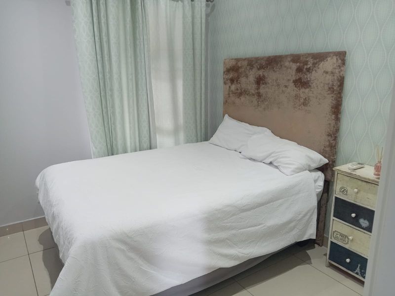 A cozy bedroom featuring tiled flooring and decorative patterned wallpaper, providing a neutral foundation for personal styling.