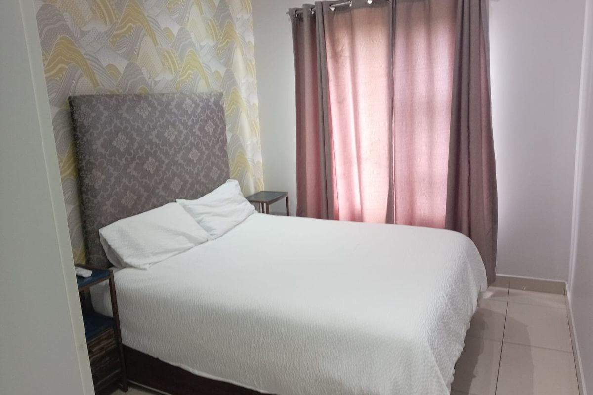 A well-maintained bedroom featuring neutral tiled flooring and a decorative feature wall, providing a comfortable and clean living space.