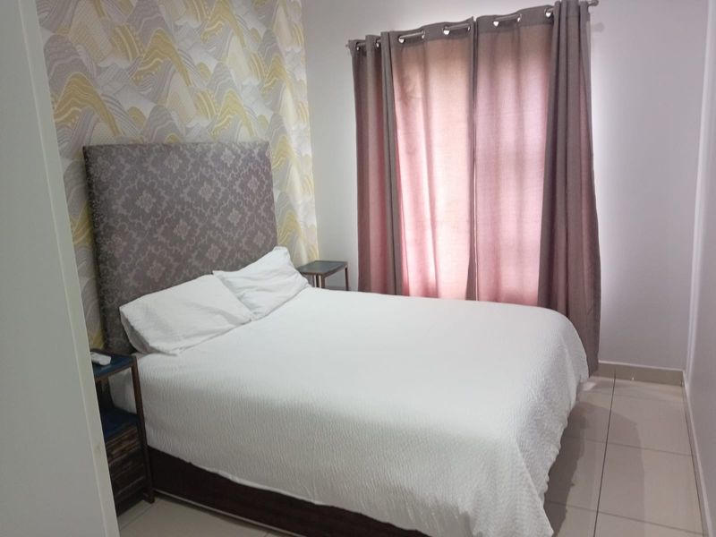 A well-maintained bedroom featuring neutral tiled flooring and a decorative feature wall, providing a comfortable and clean living space.