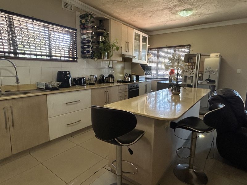 A functional kitchen featuring light-toned cabinetry, stone countertops, a central island, and integrated appliances, offering a practical layout for cooking and casual dining.