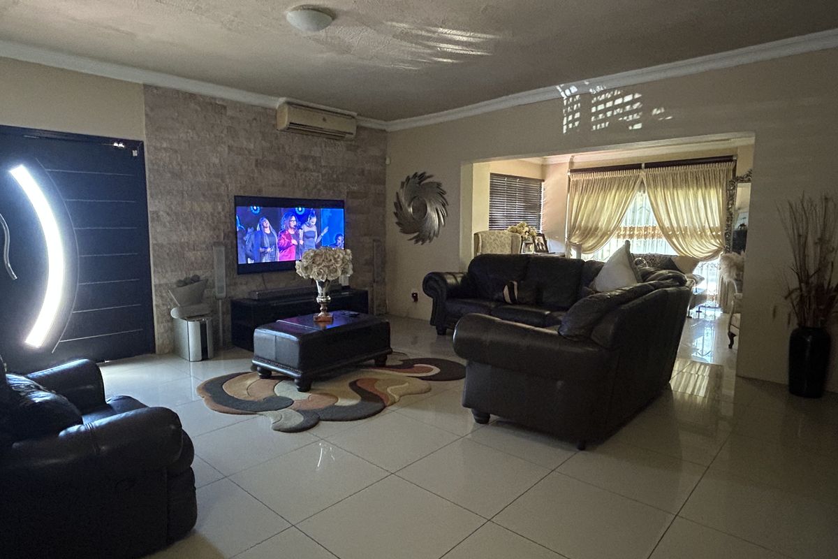 Spacious living room featuring large format floor tiles, a stone-clad feature wall, and a wall-mounted air conditioning unit.