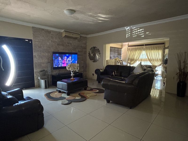 Spacious living room featuring large format floor tiles, a stone-clad feature wall, and a wall-mounted air conditioning unit.