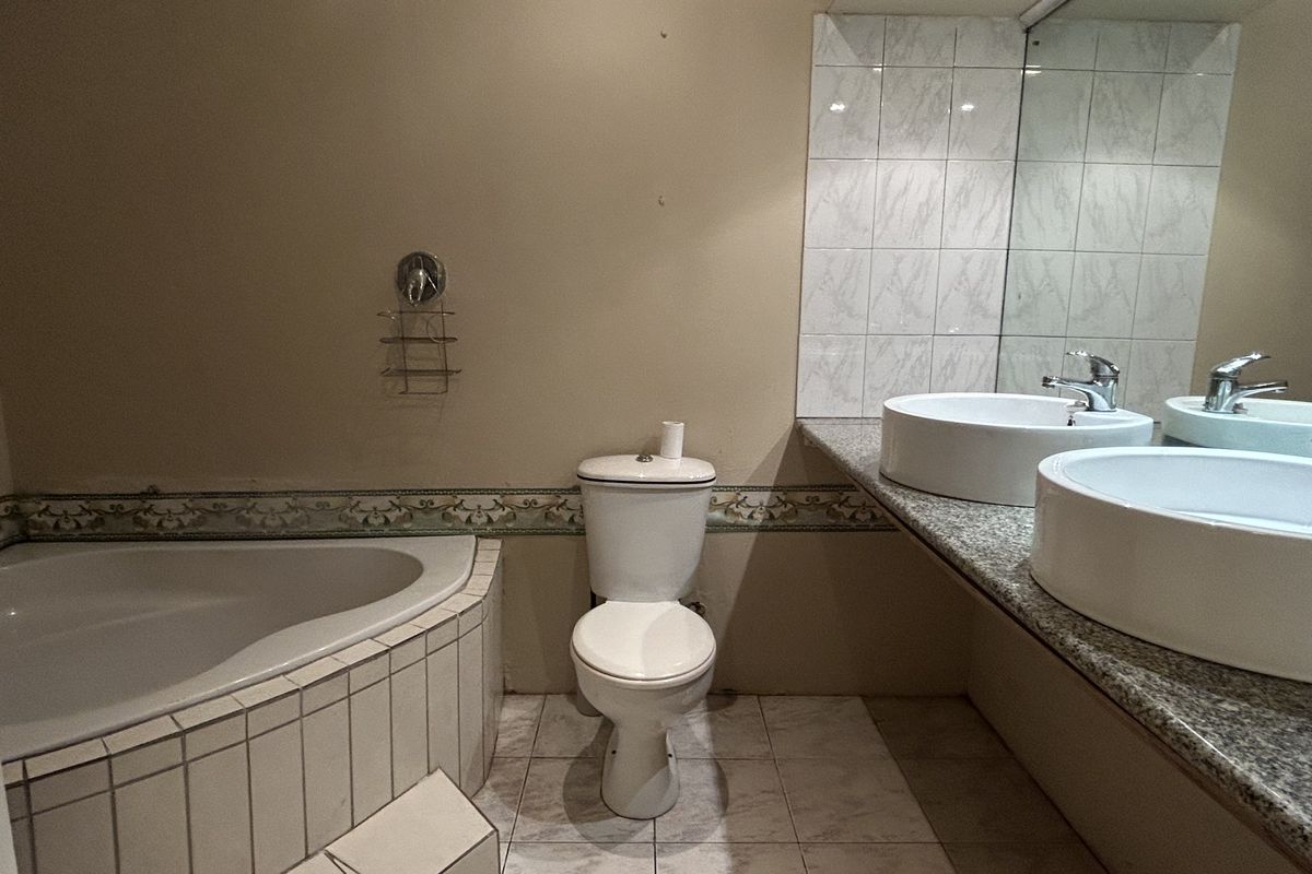 A functional bathroom featuring a corner bathtub, dual vessel sinks on a granite vanity, and a large wall mirror.