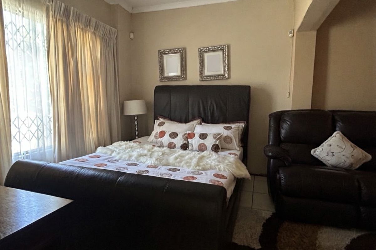 A bedroom featuring tiled flooring and a window fitted with a security gate.
