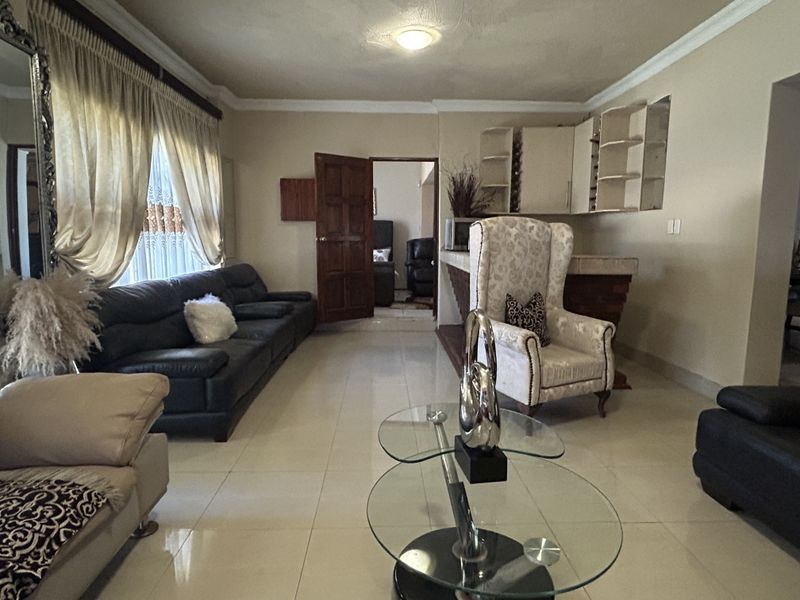 Open plan living area featuring tiled flooring, crown molding, and a built-in bar area with shelving.