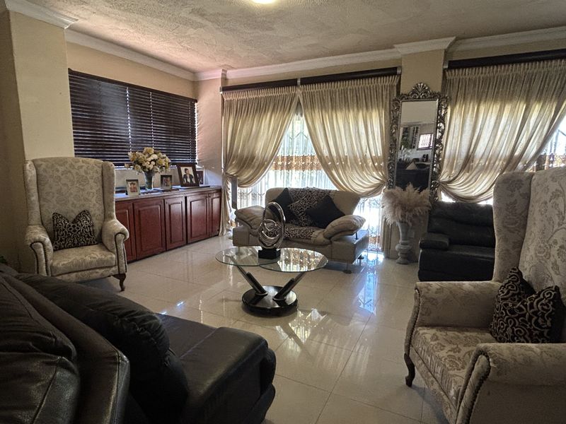 A spacious living room featuring tiled flooring, built-in cabinetry, and large windows with window treatments.