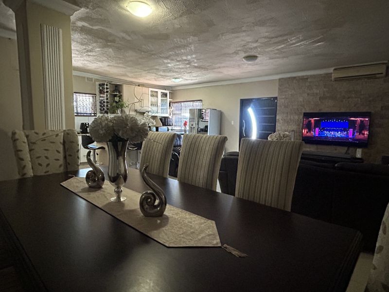Open-plan living and dining area featuring a stone feature wall, integrated kitchen cabinetry, and recessed lighting, creating a functional and connected living space.