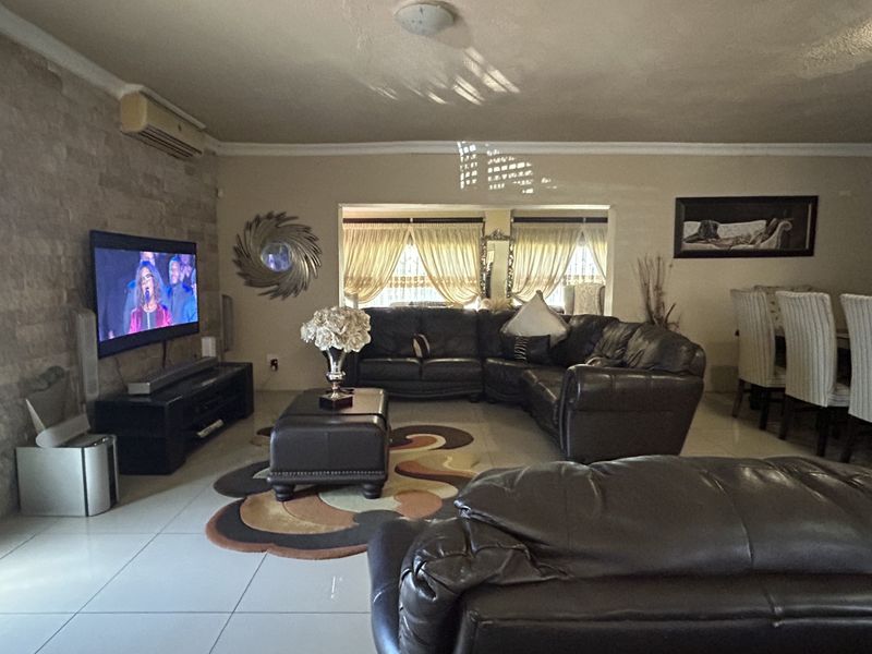 Spacious living room featuring a stone accent wall, tiled flooring, and a split-system air conditioner, with an adjacent dining area visible.