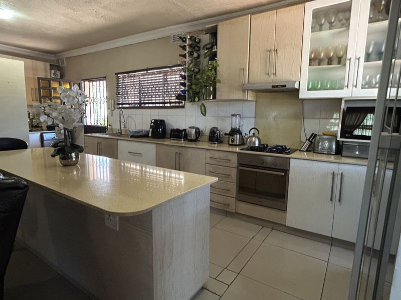 A functional kitchen featuring a central island with stone countertops, built-in oven, gas hob, and ample cabinetry, offering a practical layout for daily use.