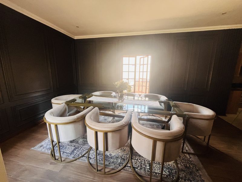 Elegant dining room featuring dark paneled walls, recessed lighting, and French doors that provide natural light.