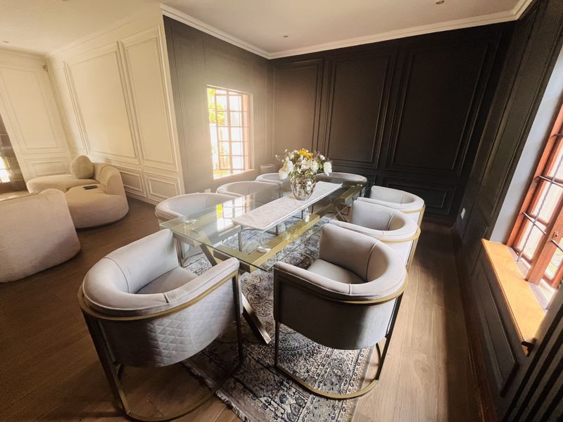 Elegant dining room featuring sophisticated dark wainscoting, timber flooring, and large windows that provide ample natural light.