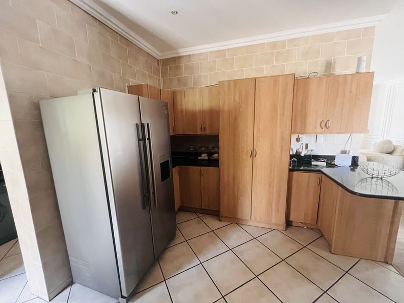 A functional kitchen featuring wooden cabinetry, granite countertops, tiled flooring, and a tiled wall finish, providing ample storage and workspace.