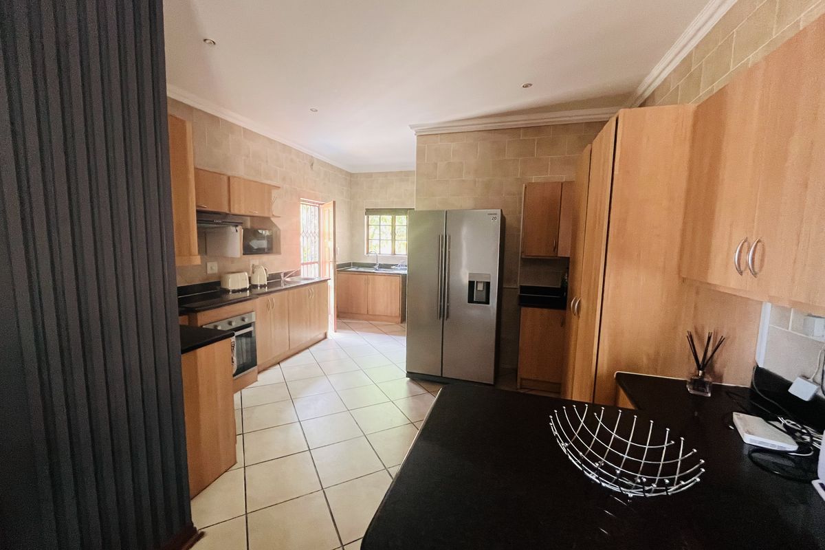 Spacious kitchen featuring light wood cabinetry, dark granite countertops, built-in oven, extractor fan, and tiled flooring with ample storage space.