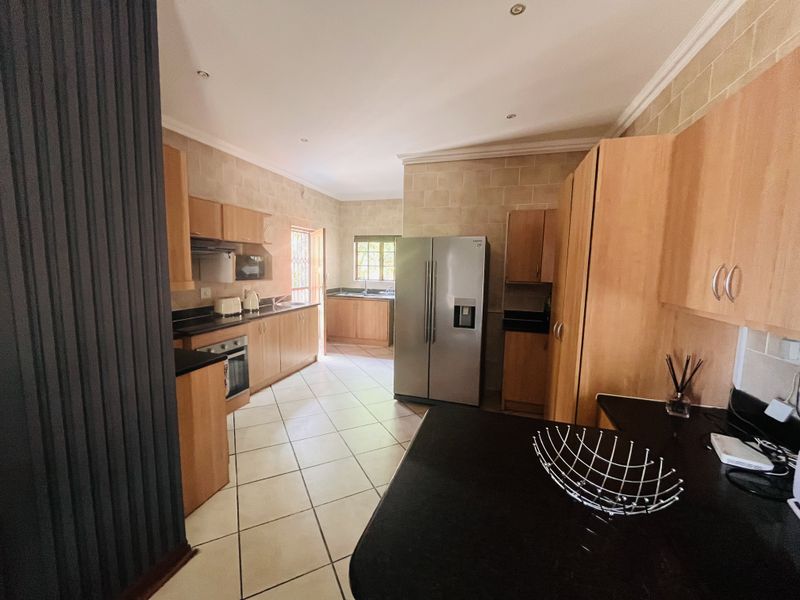 Spacious kitchen featuring light wood cabinetry, dark granite countertops, built-in oven, extractor fan, and tiled flooring with ample storage space.