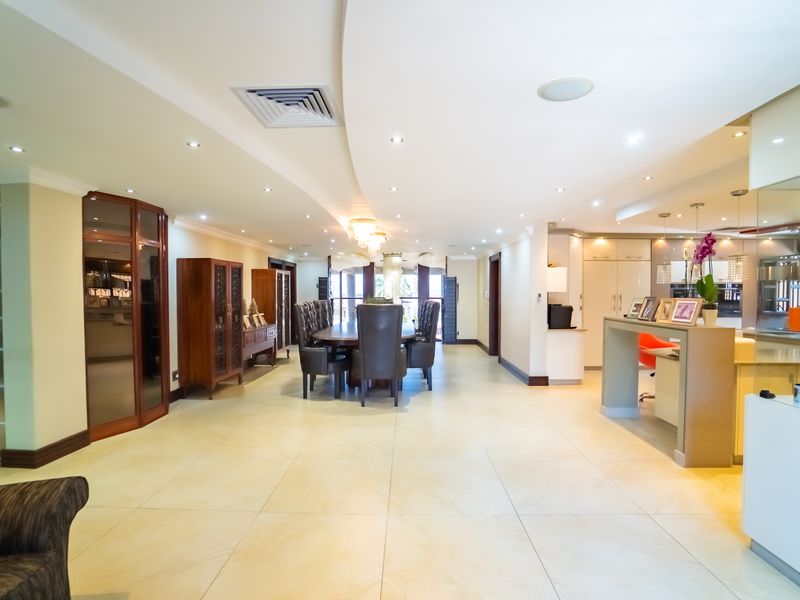 Spacious open-plan living and dining area featuring tiled flooring, recessed ceiling lighting, and a modern breakfast bar with integrated cabinetry.