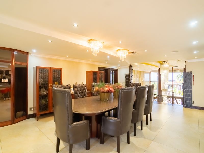 Spacious dining room featuring elegant crystal chandeliers, recessed lighting, and polished tile flooring, creating a sophisticated atmosphere for formal entertaining.
