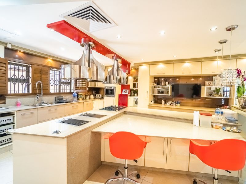 Modern kitchen featuring extensive built-in cabinetry, stone countertops, integrated gas hob and grill, dual stainless steel extractor fans, and recessed lighting.