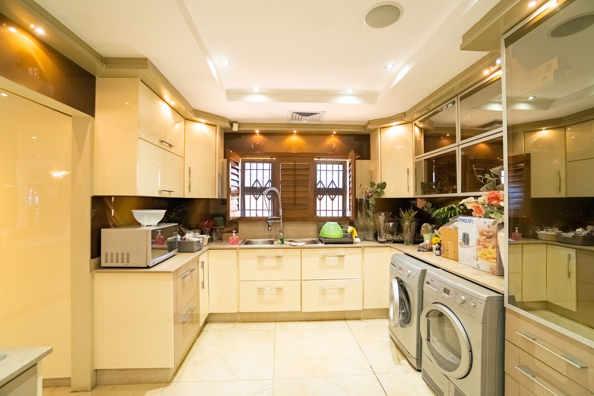 A well-appointed kitchen featuring high-gloss cabinetry, tiled flooring, recessed lighting, and integrated laundry appliances, offering a functional and modern workspace.