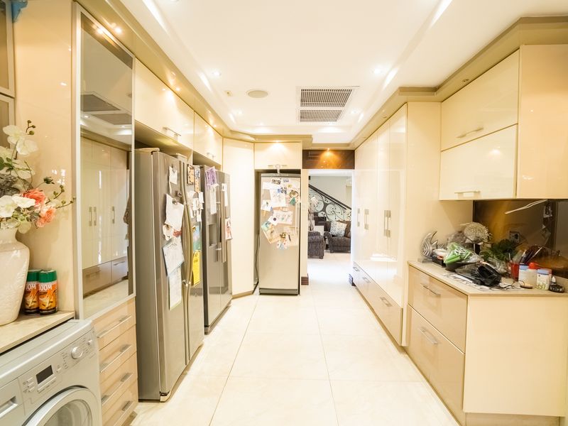 A well-appointed scullery featuring extensive built-in cabinetry, integrated appliances, tiled flooring, and recessed lighting, providing ample storage and utility space.
