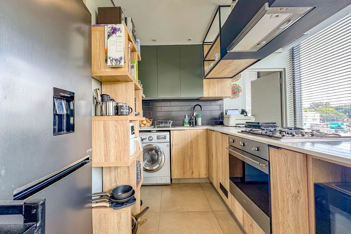 Modern kitchen featuring wood-finish cabinetry, stone countertops, integrated appliances including a gas hob, oven, and washing machine, complemented by a stylish subway tile backsplash.