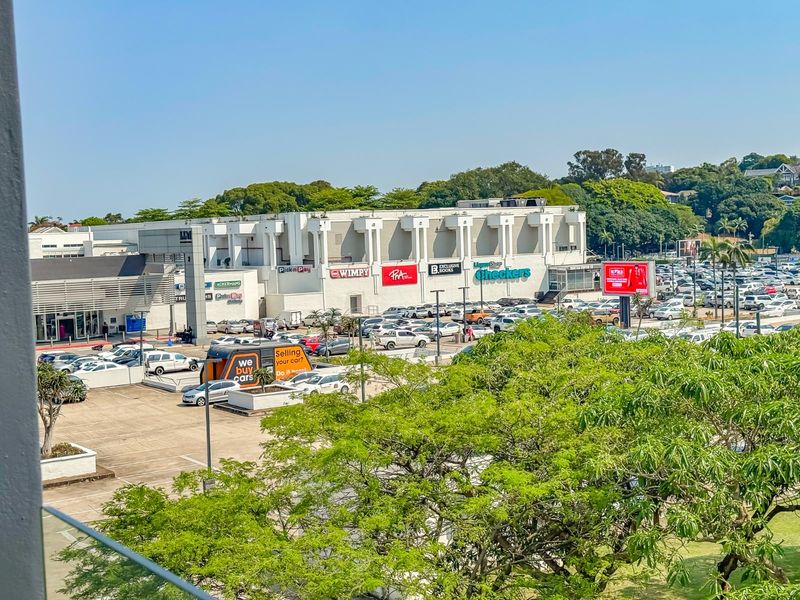 Elevated view overlooking a commercial shopping center and adjacent parking area.