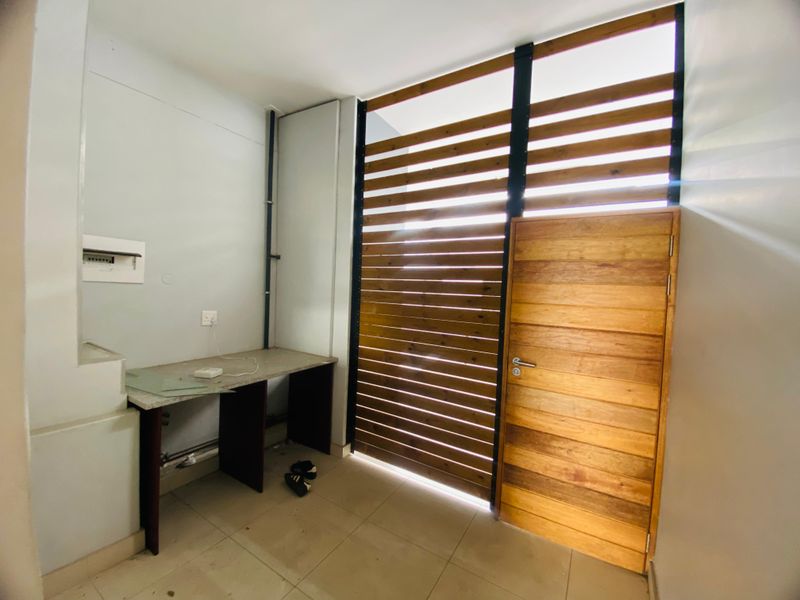 A functional utility space featuring a built-in desk, tiled flooring, and a distinctive timber slat screen with an integrated wooden door.