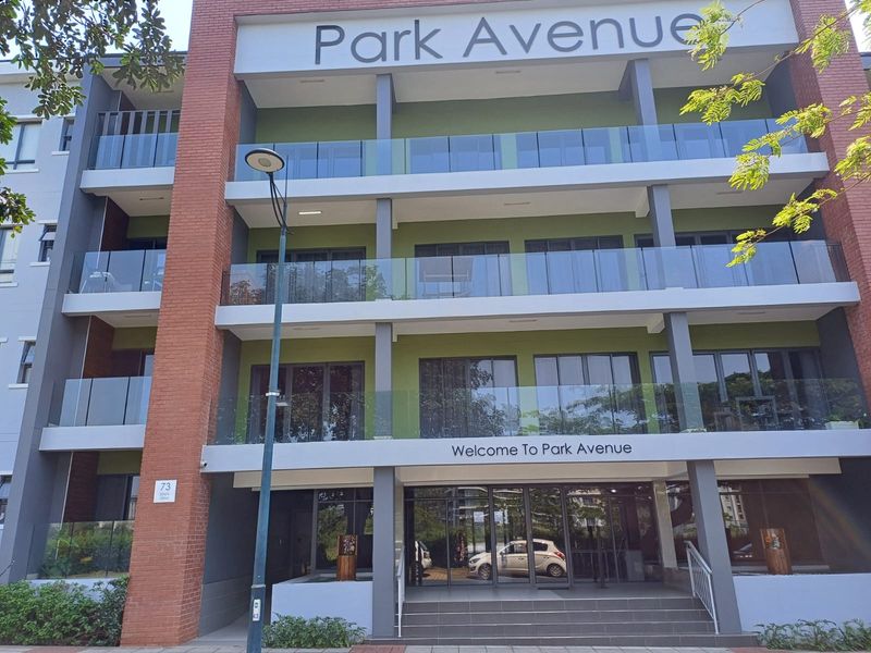 Front elevation of Park Avenue apartment complex featuring modern brick and concrete architecture with glass-fronted balconies and a welcoming ground-floor entrance.