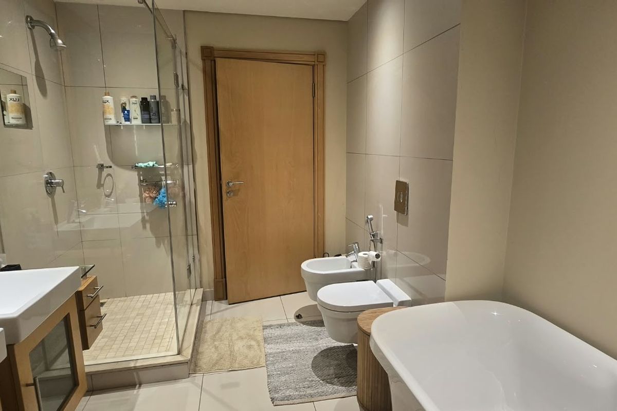 Modern bathroom featuring a double vanity, glass-enclosed shower, wall-mounted toilet, bidet, and a sleek freestanding bathtub with contemporary finishes.