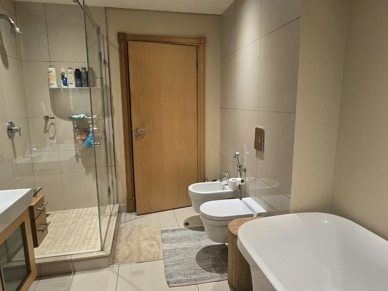 Modern bathroom featuring a double vanity, glass-enclosed shower, wall-mounted toilet, bidet, and a sleek freestanding bathtub with contemporary finishes.