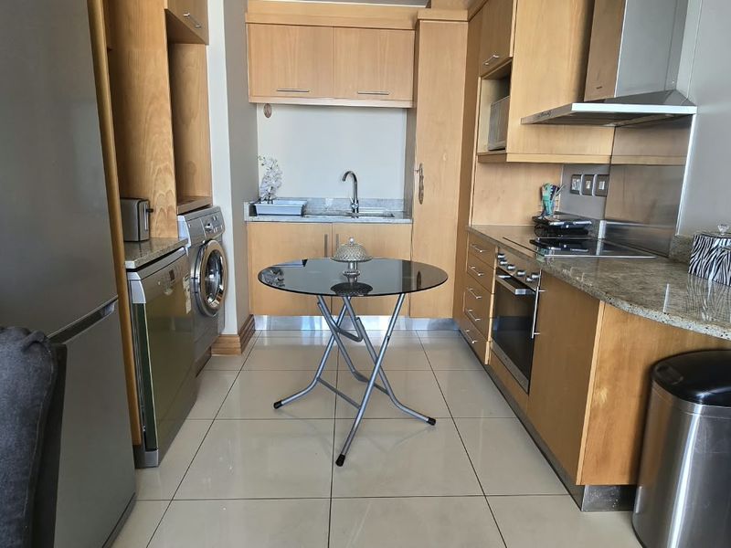 Compact kitchen featuring light wood cabinetry, granite countertops, integrated appliances, and tiled flooring, offering a functional and efficient workspace.