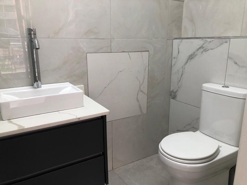 Modern bathroom featuring marble-effect wall tiles, a sleek vanity cabinet with a basin, and a standard toilet.