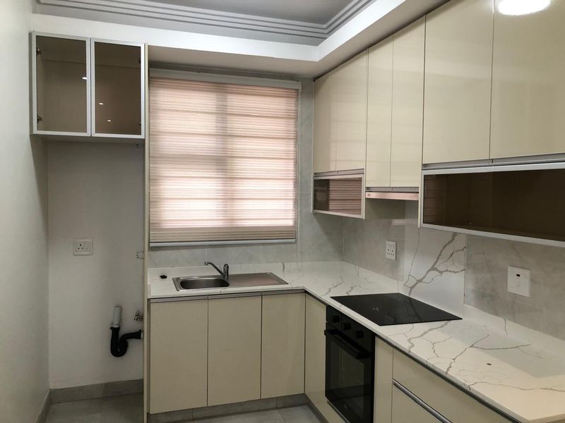 Modern kitchen featuring high-gloss cabinetry, stone countertops with marble-effect backsplash, integrated oven, and hob, offering a clean and functional culinary space.